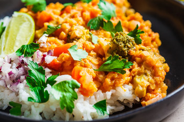 Vegetarian lentil curry with rice in black plate. Healthy vegan food concept.