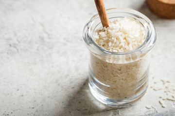 Raw white rice in glass jar, copy space. Cooking food concept.