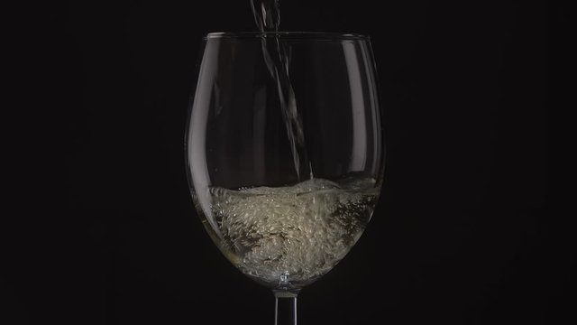 the wine is poured into a glass a black background, closeup