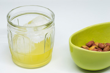 lemon liqueur liquor in glass cup with ice and bowl with peanuts
