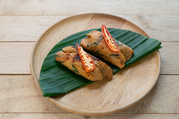 Grilled fish with curry paste and coconut milk on banana leaf in wooden dish,Thai food.