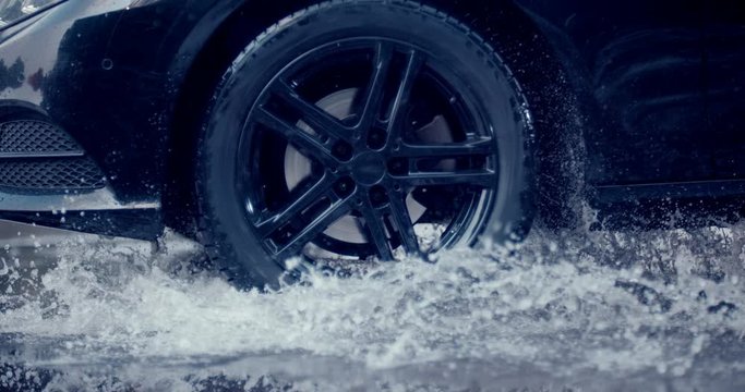 A large stream of spray erupts from under the wheels, flying far around. Slow mo, slo mo, slow motion, high speed camera Phantom