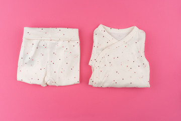  baby clothes on pink background top view