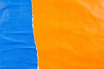 Blue and orange crumpled, torn and peeling paper posters and placards on rough surface texture...