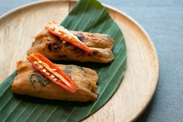 Grilled fish with curry paste and coconut milk on banana leaf in wooden dish,Thai food.