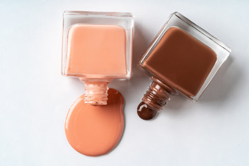 Nude colors nail polish spilled over white background