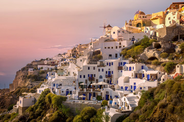 Little houses in the cliff at the city of Oia in Santorini, Greece. .Pink skies fills the skyTravel, city, explore, and summer concept.