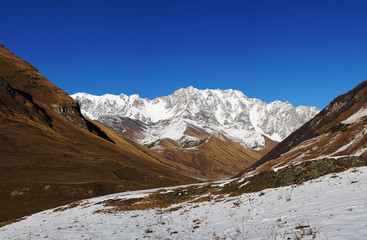 Mountain landscape panorama. Majestic mountain peaks covered with snow against a bright blue sky.