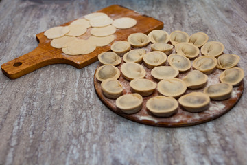Sculpt pierogy and pelmeni concept. Include rustic cutting board, making pierogies on a rustic wooden table. dumplings