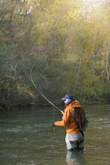 fly fisherman in river in autumn