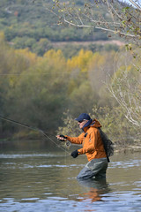 fly fisherman in river in autumn