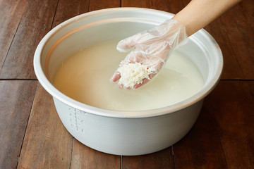 Hands dropping rice grain aluminum pot,Cook rice concept.