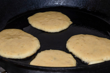 Cooking wheat pancakes for american breakfast on black griddle