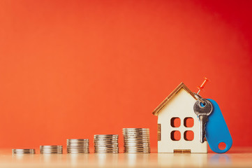 coins house and key on wooden and red background