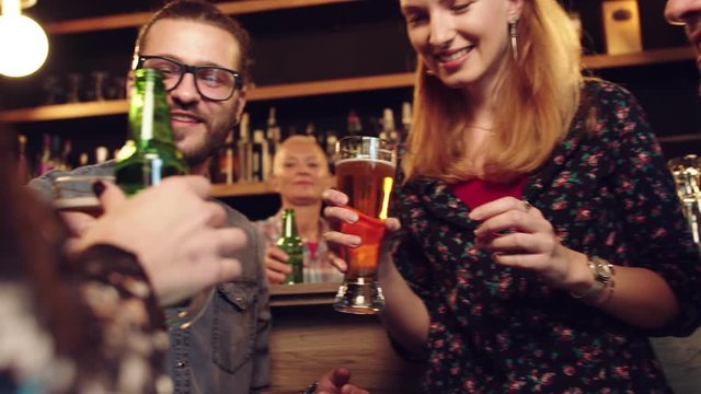 Friends standing in bar and toasting with beer.