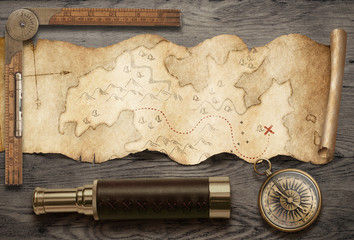 Old torn treasure map with compass and spyglass top view still life. Adventure and travel concept. Mixed media.