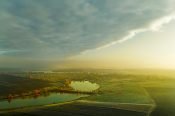 Naklejka premium Fog is approaching the autumn meadow with the lake.