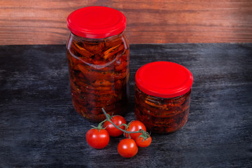 Sundried tomatoes in olive oil in glass jars, fresh tomatoes