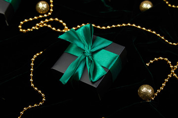 Christmas festive black gift boxes with green ribbon on velours glitte, shine gold  background. Copy space. Flat lay. Festive holiday mood.