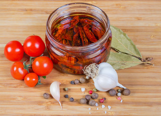 Dried tomatoes in olive oil in glass jar and ingredients