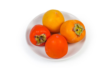 Different persimmon fruits on white dish on a white background