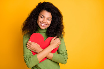 Photo of curly wavy satisfied pleased cheerful girl at leisure embracing gifted heart smiling...