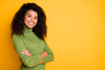 Fototapeta premium Photo of cheerful positive curly wavy cute nice pretty girl smiling toothily with hands folded near empty space isolated vibrant color background