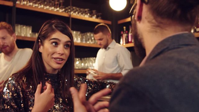Young caucasian woman chatting with her friend while standing at pub.