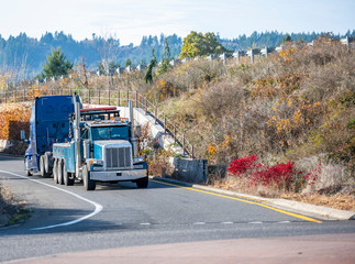 Fototapeta na wymiar Blue big rig tow truck towing broken big rig semi truck driving on the highway exit