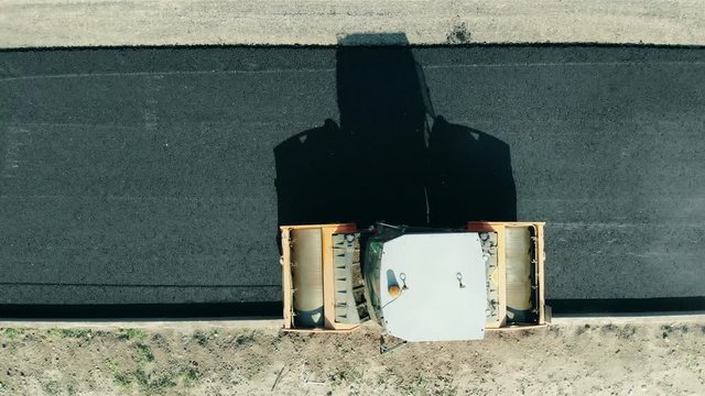 Top view of a rolling machine riding along fresh asphalt. Road construction process.