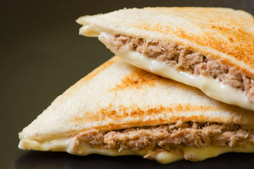 Close up of sandwich stuffed with salad sauce and dried Tuna in black dish.