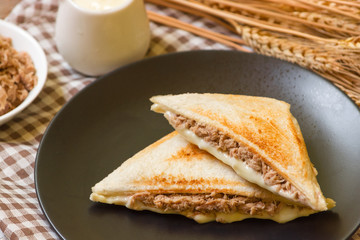 Sandwich stuffed with salad sauce and dried Tuna in black dish on wooden table.