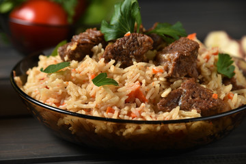 Oriental cuisine. National Uzbek pilaf with meat on a wooden table. Top view, copy space.