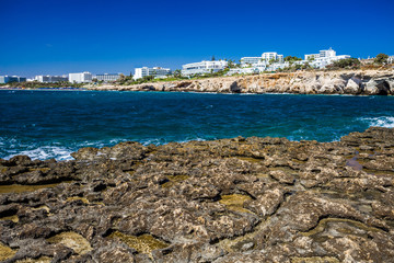 Fototapeta na wymiar Rocky shore, clear turquoise sea water and blue sky in Ayia-Napa, Cyprus, hotels.