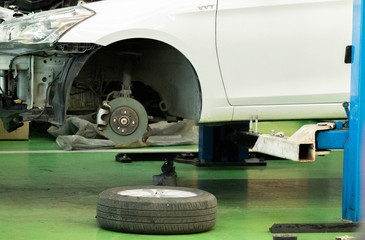 Car brakes with wheels that have been removed and parts removed for repair. There are rubber shock absorbers in the repair area of the garage.