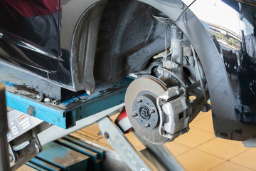 Car brakes with wheels that have been removed and parts removed for repair. There are rubber shock absorbers in the repair area of the garage.