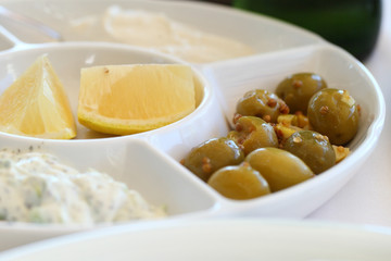 Green olives, lemon and yogurt tzatziki in a plate, food appetizer.