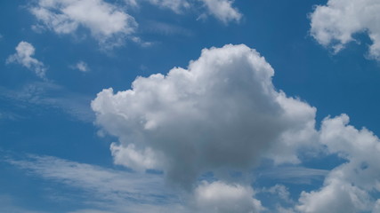 Ant's eye view of fat white clouds moving in strong wind with blue sky background.