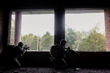 Two military soldiers shoot from the Windows at the terrorists sitting in ambush in the building....