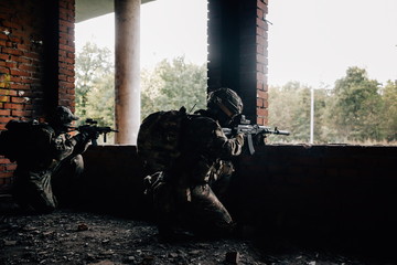 Two military soldiers shoot from the Windows at the terrorists sitting in ambush in the building