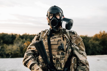 Portrait of a military soldier in a smoke curtain with an assault rifle in a gas mask