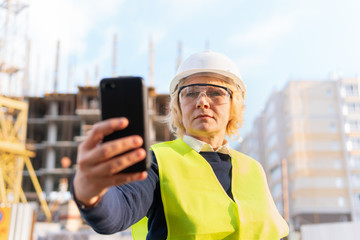 A female builder worker at a construction site works and controls the process.