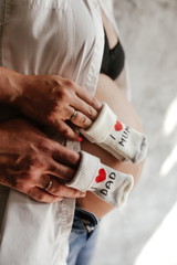 Obraz premium Pregnant girl hugging a man holding in front of her socks for the baby with the words I love dad, I love mom vertical photo