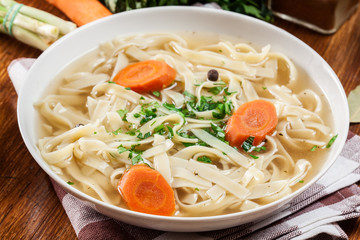 Tasty meat broth with noodles, carror and parsley