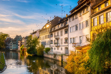 Scenic and iconic cityscape of historic Petite France disctrict, downtown Strasbourg, on a sunny late afternoon. Houses along the Ill river. - obrazy, fototapety, plakaty