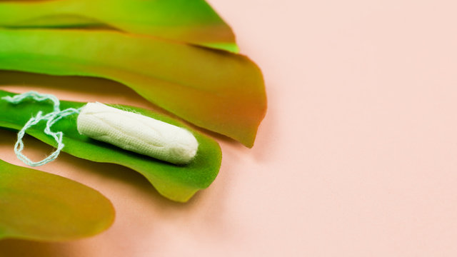Menstruation cotton tampon on pink background with copy space