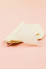 Close up of menstrual cup in cotton bag on pink background
