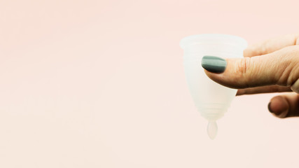 Close up of woman hand holding menstrual cup in cotton bag