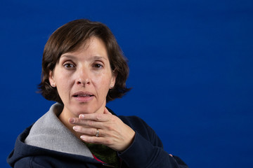 Woman on a blue background looking at the camera confidently.