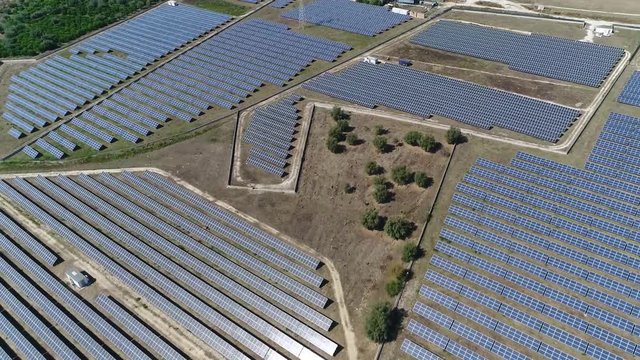 Aerial footage moving over photovoltaic station also known as a solar park or farm is large-scale PV system designed for the supply of merchant power into the electricity grid by sunlight 4k quality